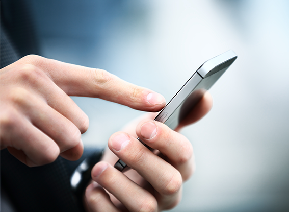 A person uses their index finger to touch the screen of a smartphone held in their other hand.