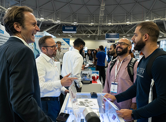 Exhibitors and attendees laugh as they discuss products available at the booth