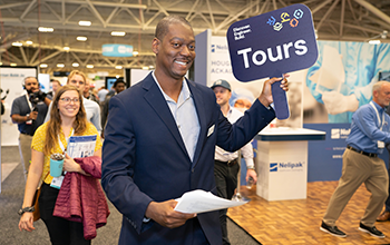 Tour guide holds sign to direct attendees to the next stop on their tour
