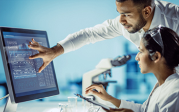 Two researchers review findings on a computer screen