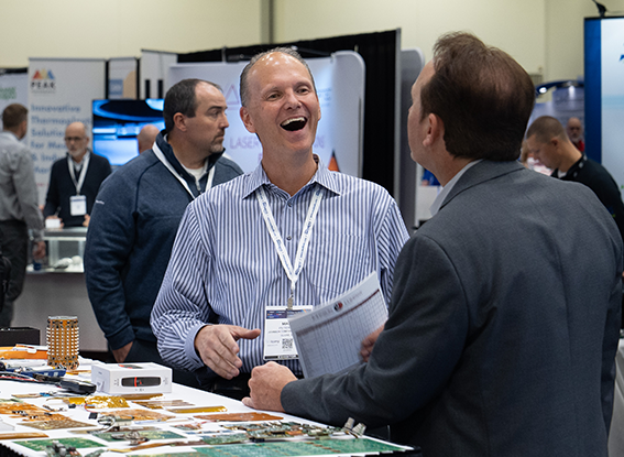 Attendee laughs as he speaks to an exhibitor at MD&M Midwest