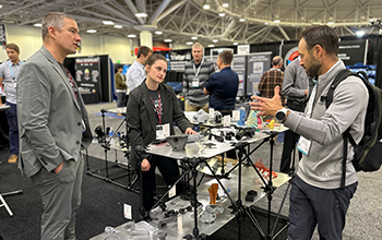 Attendee speaks to two exhibitors about their medtech products.