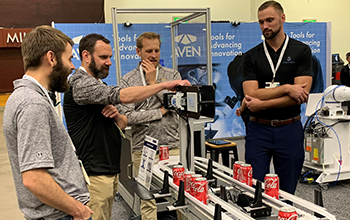 Attendees witness automation of Coca-Cola can on a conveyor