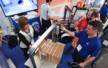 Exhibitors demonstrate packaging product on the show floor.