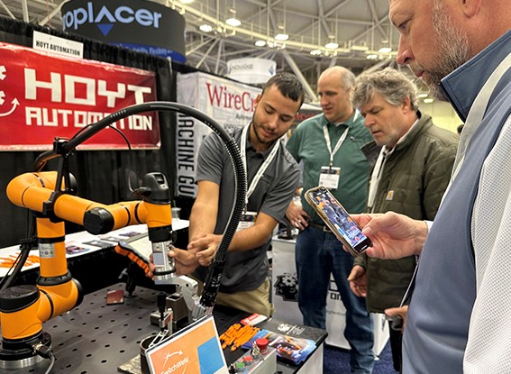Exhibitor demonstrates automation equipment to onlookers